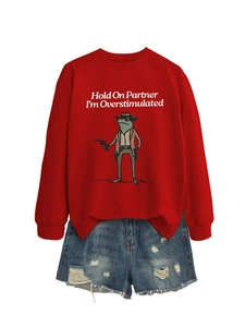 Detail of red crewneck sweatshirt featuring funny frog print and distressed denim shorts