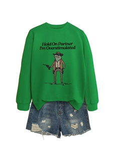 Close-up of green crewneck sweatshirt with cowboy frog print and distressed denim shorts
