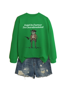 Close-up of bright green sweatshirt featuring a funny frog graphic and distressed denim shorts