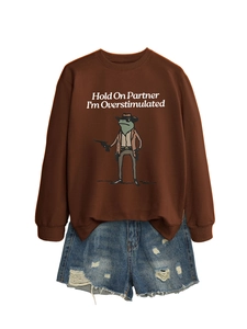 Detail of brown sweatshirt featuring funny frog print and blue distressed denim shorts