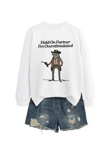 Detail of white sweatshirt with funny frog cowboy graphic and distressed denim shorts