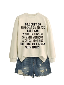 Close-up of cream crewneck sweatshirt with black text slogan and frayed denim shorts