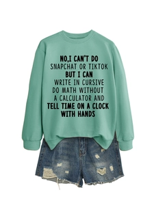 Detail of mint green sweatshirt with black slogan print paired with frayed denim shorts