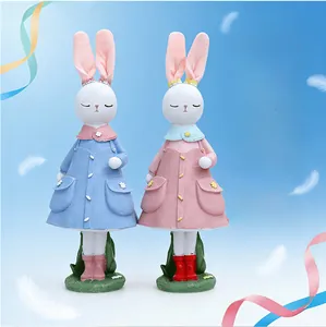 Dettaglio di figurine di coniglietti pasquali in resina con cappotti blu e rosa
