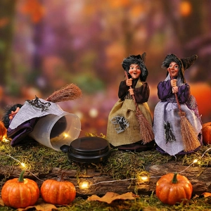 Three Halloween witch figurines with pointed hats and brooms on mossy wood base