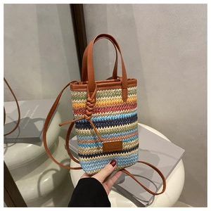 Detail of colorful woven phone bag with brown leather trim and fashion tag
