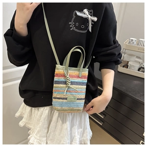 Detail view of a woven colorful striped straw crossbody phone bag with leather strap