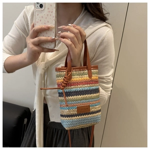 Detail of colorful striped woven tote bag featuring brown leather handles and fashion patch