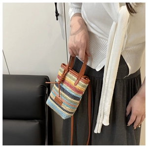 Detail of colorful woven mini crossbody bag with fashion patch and brown leather strap