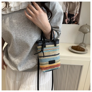 Macro detail of the colorful woven texture and black leather handle on the crossbody bag