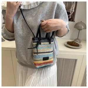 Close-up of colorful woven straw phone bag with fashion label and leather handle details