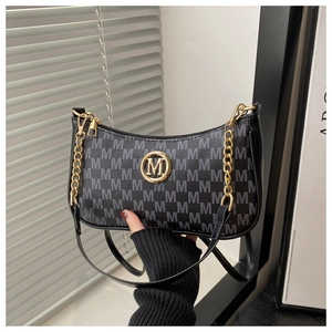 Detail of black underarm bag featuring gold M logo and repeating letter pattern