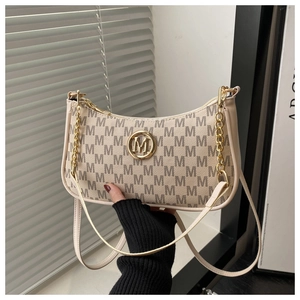 Detail of cream monogram underarm bag with gold M logo and elegant chain strap
