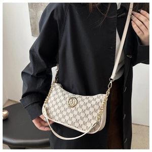 Close-up of vintage monogram printed crossbody bag with golden M-shaped logo detail