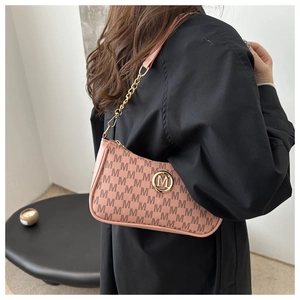 Pink crescent underarm bag with monogram print and golden M logo shown on a model