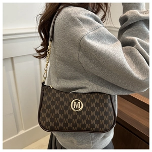 Detail of vintage brown shoulder bag featuring gold M logo and leather chain strap