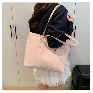Detail of pink tote bag with crinkled texture fabric and slim shoulder straps on model
