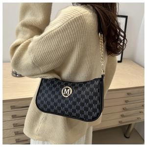 Close-up of black crossbody bag with M-pattern print and gold metallic logo detail