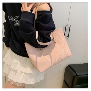 Detailed texture of pink tote bag with stylish pleated pattern and metal rivet handles