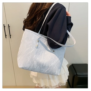 Detailed close-up of light blue marble-textured tote bag with gold metal rivet accents