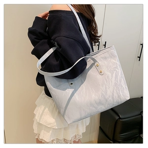 Dettaglio borsa tote grigio chiaro con texture increspata e borchie dorate
