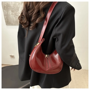 Detail view of burgundy glossy crescent shoulder bag with adjustable golden buckle strap