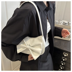 Detailed view of a white half-moon shoulder bag featuring a large decorative bow