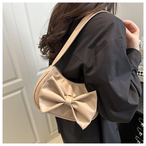 Détail d'un sac à bandoulière beige en cuir PU avec un grand nœud décoratif en relief