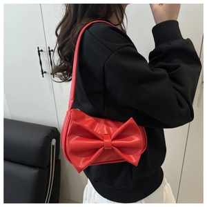 Detail of red leather shoulder bag with oversized 3D bow and sleek metallic zipper