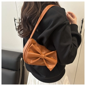 Close-up of brown PU leather underarm bag featuring a large decorative bow design