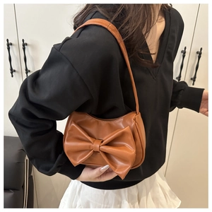 Caramel bow shoulder bag styled with a black top for an elegant summer fashion look