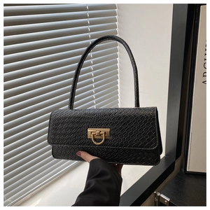 Detail of black faux crocodile leather baguette bag with premium gold metal clasp hardware