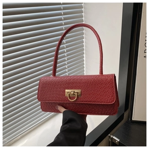 Detail of red baguette bag with crocodile texture and gold U-shaped metal buckle