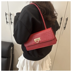 Model showing side view of a red crocodile-embossed baguette bag with gold horseshoe clasp