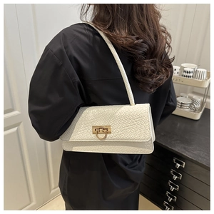 Close-up of white woven baguette bag on shoulder showing texture and gold buckle
