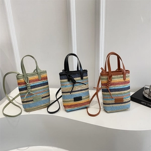 Three colorful woven straw tote bags with leather handles on a white minimalist display