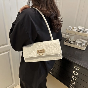 Minimalist white baguette bag with woven texture and gold clasp worn by a model