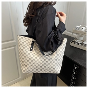 Detail of spacious tote bag featuring letter print patterns and reinforced rivet straps