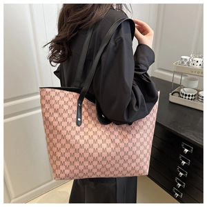 Detail of pink tote bag with M-letter print and black leather handles shown on model