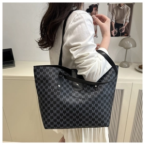 Detail of grey patterned tote bag with all-over M-print and black leather straps