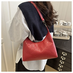 Detail of red woven leather shoulder bag showing intricate grid texture and gold hardware