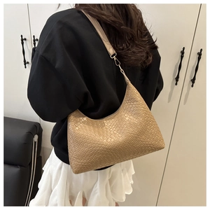 Close-up of a light brown crescent Hobo bag with textured faux leather pattern on a model