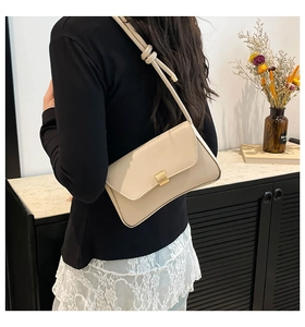 Detail of off-white baguette bag with gold metal buckle and knotted strap detail