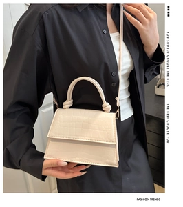Detail of cream faux crocodile leather handbag with twisted handle and gold hardware