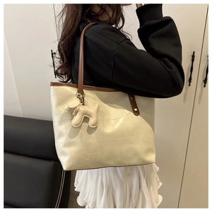 Détail du cabas blanc cassé avec coutures géométriques et anses en cuir marron
