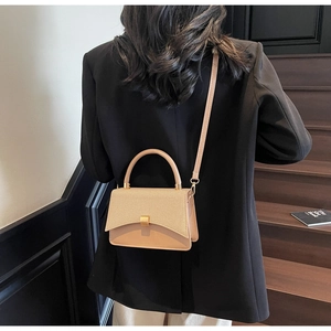 Détail du sac bandoulière abricot avec rabat tressé et fermoir métallique doré
