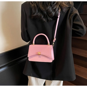 Vue de dos d'un mannequin en blazer noir avec un sac à bandoulière carré rose contrasté