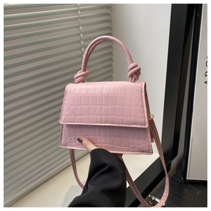 Close-up of pink crocodile texture on square handbag with a knotted handle detail