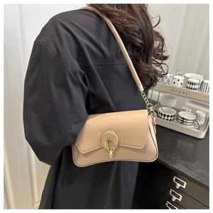 Detailed side view of beige leather shoulder bag with gold metal buckle on female model