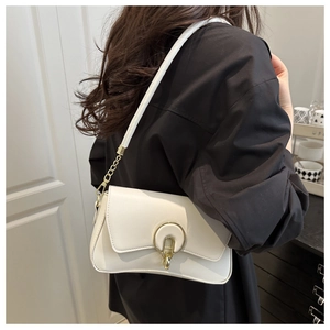 Detail of white leather underarm bag featuring a gold round lock and metal chain strap